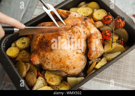 Der Prozess der Schneiden das fertige Gericht, gebraten, knusprig, lecker Huhn in Anteile für die Thanksgiving. Stockfoto