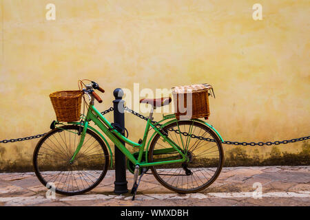 Italien, Apulien, Provinz Lecce, Lecce. Damen Fahrrad, mit Weidenkörbe, hielten gegen einen Pfosten. Stockfoto