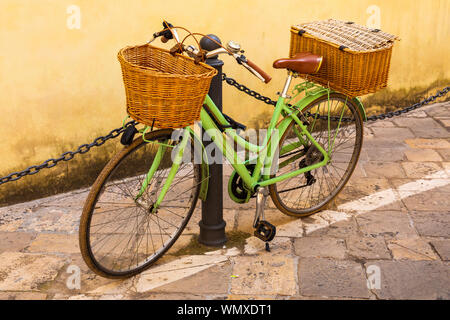 Italien, Apulien, Provinz Lecce, Lecce. Damen Fahrrad, mit Weidenkörbe, hielten gegen einen Pfosten. Stockfoto