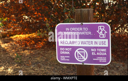 Ein Schild warnt Leute, die zurückgeforderte Wasser in der Landschaft, Wasser zu konservieren Stockfoto