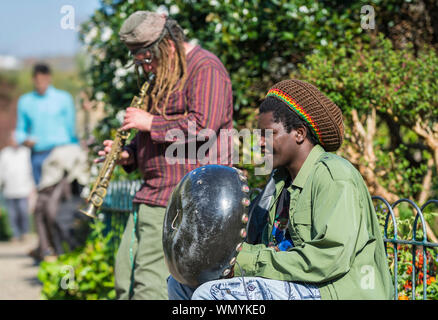 Paar Straßenmusikanten spielen von Instrumenten in einem Park in Großbritannien. Straßenmusikanten Straßenmusik und unterhaltsam in einem Park in Brighton, East Sussex, England, UK. Stockfoto