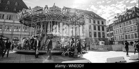 Straßburg, Frankreich - Apr 8, 2019: die Menschen Fußgänger Besucher die Stadt genießen und Merry-go-round in zentraler Ort Gutenberg - Schwarz und Weiß Stockfoto