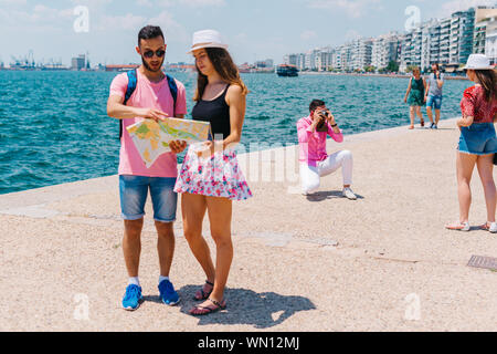 Ein paar ist das Lesen einer Karte, während die anderen Fotos ist, die ihren Sommer Urlaub. Stockfoto