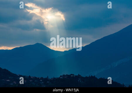 Sonnenstrahlen durch die Wolken über den Bergen in der Lombardei, Italien Stockfoto