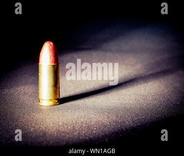 Einen einzigen Ständigen 9 mm bullet mit dramatischen Seite Licht und Schatten Stockfoto