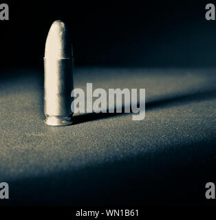 Einen einzigen Ständigen 9 mm bullet mit dramatischen Seite Licht und Schatten in seliumn Ton Stockfoto