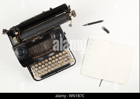 Vintage Retro Schreibmaschine und öffnen Sie Notizbuch mit Kugelschreiber auf weissem Holztisch, Hintergrund, oben flach von oben - Journalismus oder Schriftsteller conc Stockfoto