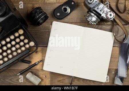 Vintage Retro Schreibmaschine, analogen Filmkamera und öffnen Sie Notizbuch mit Kugelschreiber auf braune Holztisch, Hintergrund, oben flach von oben - journ Stockfoto