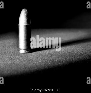 Einen einzigen Ständigen 9 mm bullet mit dramatischen Seite Licht und Schatten in Schwarz und Weiß Stockfoto