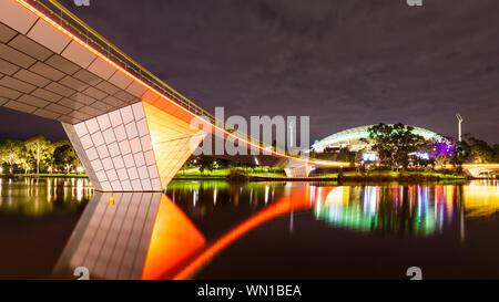 Der Fluss Torrens Fußgängerbrücke durch die Nacht, mit Adelaide Oval Sports Arena im Hintergrund. Adelaide Australien. Stockfoto