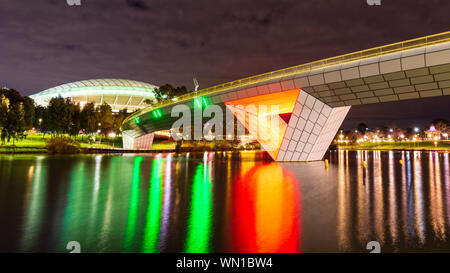 Der Fluss Torrens Fußgängerbrücke durch die Nacht, mit Adelaide Oval Sports Arena im Hintergrund. Adelaide Australien. Stockfoto