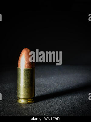 Einen einzigen Ständigen 9 mm bullet mit dramatischen Seite Licht und Schatten Stockfoto