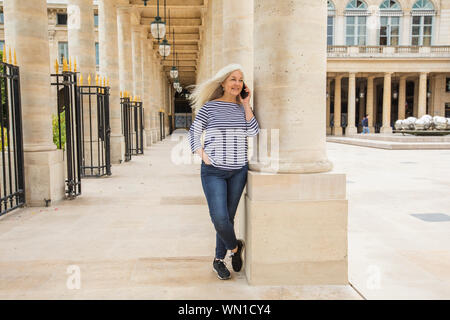 Frau am Telefon durch Spalten des Palais Royal in Paris, Frankreich Stockfoto