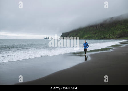 Man Joggen am Strand in Vik, Island Stockfoto