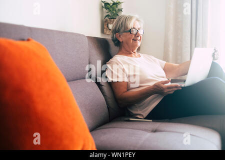 Lächelnde ältere Frau mit Laptop auf dem Sofa Stockfoto