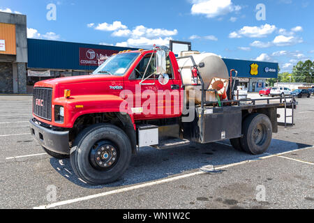 STATESVILLE, NC, USA-1 SEPTEMBER 2019: Ein helles Rot, schwere GMC Abschleppwagen Lkw, mit einem flüssigen Speicher auf dem Bett. Stockfoto