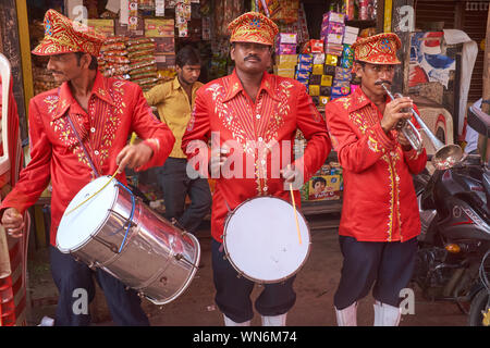 Drei uniformierten Mitglieder einer Band für Hochzeiten und andere Feierlichkeiten beschäftigt, ihre Trommeln und Trompeten spielen in einer Seitenstraße in Mumbai, Indien Stockfoto