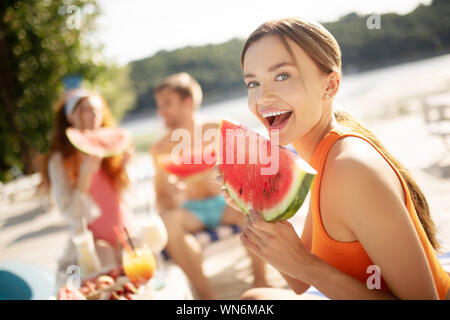 Schöne blaue Augen, lächelnde Frau beim Essen Wassermelone Stockfoto