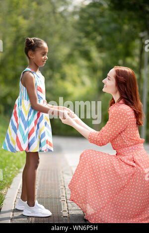 Dunkelhäutige Mädchen tragen weiße Turnschuhe am Mami suchen Stockfoto