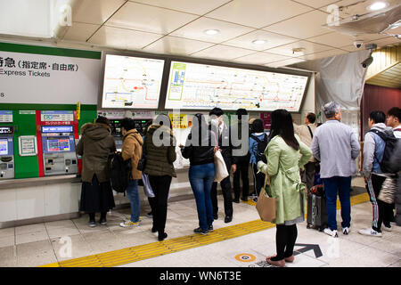 Japaner und ausländische reisende Passagiere warten und stehen in der Warteschlange für Ticket kaufen MRT Züge von auto Automaten in Ginza Station auf März Stockfoto