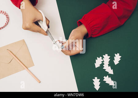 Frau schneid Weihnachtsbaum Papier mit envelopment Farbe und Papier. Noel diy Stockfoto