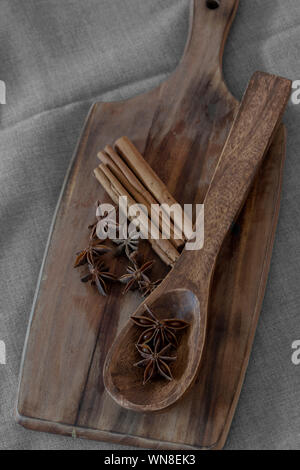 Sternanis in Löffel aus Holz mit Zimt auf Holz Schneidebrett. Aromatische Gewürze Stockfoto