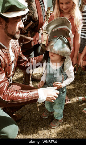 Süße 3 Jahre altes Mädchen, die versuchen, auf der ein historisches Ritter Helm auf der mittelalterlichen Festival in Vöcklabruck, Österreich zu setzen Stockfoto