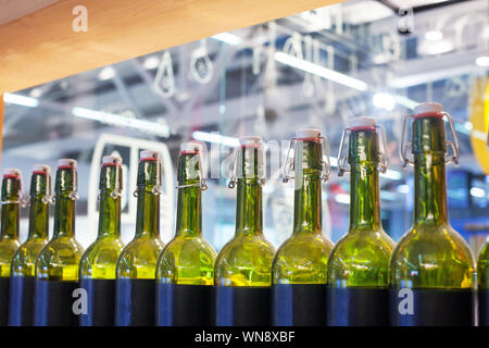 Grünes Glas Flaschen Wein in Reihe auf Holzregal, bar Interior Design, Vorbereitung von alkoholischen Cocktails, Weinprobe Konzept, Nachtleben Stil Stockfoto