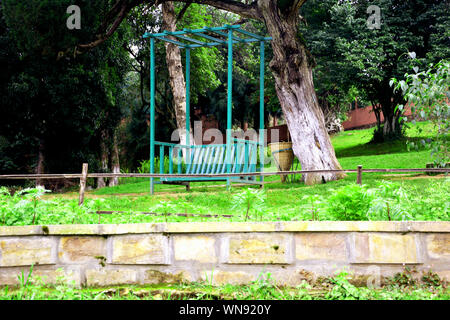 Sitzbank aus Eisen in einem Park auf einem Hügel mit Steinmauer und vielen Bäumen in den Gemeinden See von Schilling Stockfoto