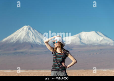 Porträt der jungen Casual blonde Frau allein reisen, kaukasische Mädchen in Hut und Sonnenbrille weg schauen mit schneebedeckten Bergen im Hintergrund. St Stockfoto