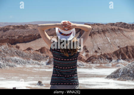 Rückseitige Ansicht des aktiven Frau, Frau sorglos Alleinreisende in Hut und lässige Kleidung bewundern Sie beeindruckende Landschaft von Moon Valley in der Atacama-wüste, Chil Stockfoto