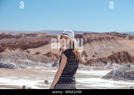 Rückseitige Ansicht des aktiven Frau, Frau sorglos Alleinreisende in Hut und lässige Kleidung bewundern Sie beeindruckende Landschaft von Moon Valley in der Atacama-wüste, Chil Stockfoto