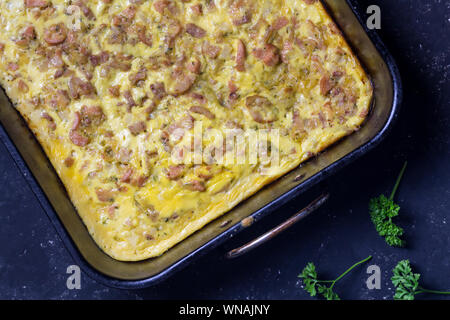 Cheesy, Speck und Würstchen, Frühstück Backen im Ofen Fach auf schwarzem Hintergrund - herzhafte Torte top Foto anzeigen Stockfoto