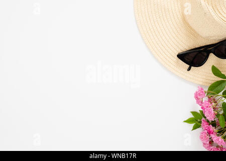 Stroh Hut, Sonnenbrille, Blumenstrauß aus rosa Rose Blumen auf weißem Hintergrund. Ansicht von oben, minimale flach Stil Komposition. Mode blog Banner mockup wit Stockfoto