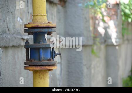 Gelbe Gasleitung vor Wohnhaus an der Wand. Stein Wand Textur Hintergrund natürliche Farbe. Stockfoto