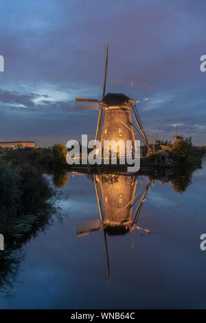 Beleuchtete Mühle spiegelt sich auf dem ruhigen Kanal Wasser während der bleu Stunde Sonnenuntergang in Alblasserdam, Niederlande Stockfoto