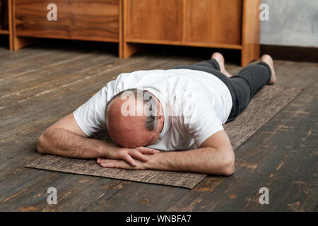 Senior alter Mann Ausruhen nach Yoga Übung auf dem Boden. Sport zu Hause für die Gesundheit. Restaurative Haltung. Stockfoto