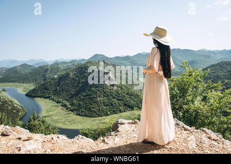 Schöne elegante Frau in einen Hut bewundert einen wunderschönen Blick auf die natürliche Landschaft und Shkadar See in Montenegro Stockfoto