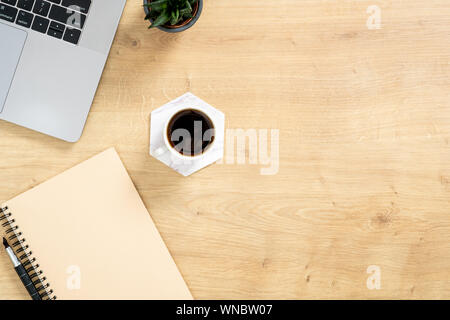 Stilvolle Büro tisch Schreibtisch. Arbeitsbereich mit Laptop, Kaffeetasse, Notizbuch aus Papier, Stift, sukkulente Pflanze auf Holz- Hintergrund. Minimale flach Stil gesundes Stockfoto