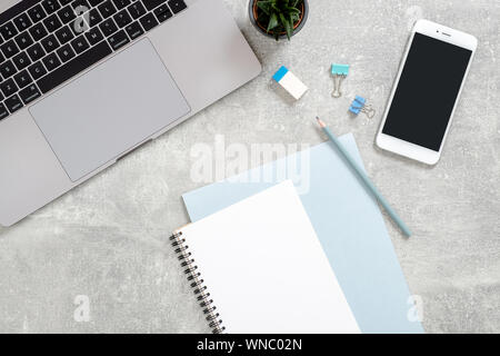 Stilvolle Büro tisch Schreibtisch. Mit laptop Arbeitsbereich, Tagebuch, sukkulente Pflanze auf Beton Stein Hintergrund. Flach, Ansicht von oben, Feminine Arbeitsbereich Stockfoto