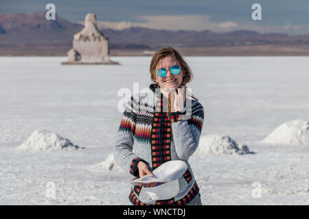 Junge Frau Porträt. Weibliche Person reisen Mädchen glücklich und lächelnd in weißen Salzsee Uyuni, Bolivien. Kaukasische Casual Model freudig trug Hut und Stockfoto