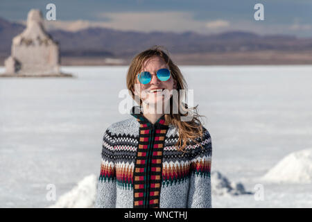 Junge Frau Porträt. Weibliche Person reisen Mädchen glücklich und lächelnd in weißen Salzsee Uyuni, Bolivien. Kaukasische Casual Model freudig trug Hut und Stockfoto