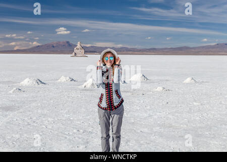 Junge Frau in voller Länge. Eine Frau auf Reisen Mädchen glücklich und lächelnd in weißen Salzsee Uyuni, Bolivien. Kaukasische Casual Model freudig trug Hut und Stockfoto