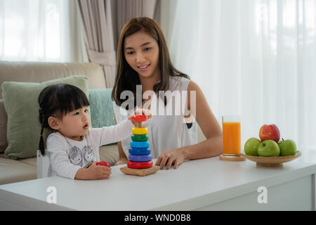 Asiatische kleinkind Mädchen mit Mutter spielen mit bunten Holzblock entwicklungspolitischen Spielzeug zu Hause. Stockfoto