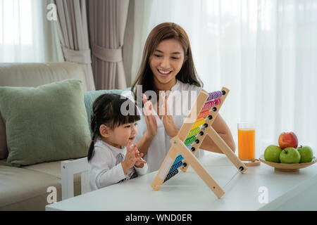 Gerne Asiatische junge Mutter und Tochter spielen mit Abacus, frühe Bildung zu Hause. Stockfoto