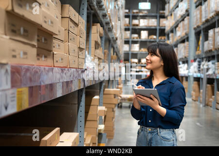 Junge asiatische Frau Prüfer oder Trainee Personal Arbeit suchen und prüft die Anzahl der Elemente speichern von digitalen Tablet. Asiatische Eigentümer oder Small Business conce Stockfoto