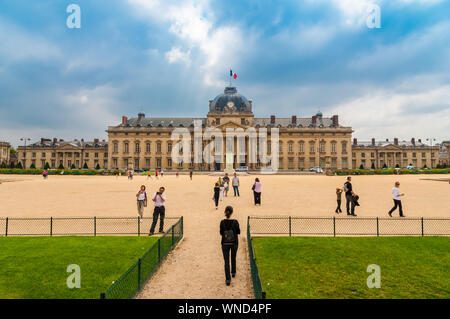 Eine Frau geht aus dem Champ-de-Mars Park in Paris an der École Militaire, eine aktive militärische Akademie und klassifiziert als National Monument. Kann es sein... Stockfoto