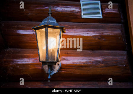 Altmodische Lampe leuchtet auf Holz- Haus, Outdoor. Stockfoto