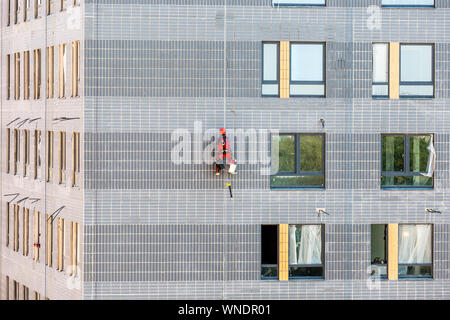 Moskau, Russland - Juni 6, 2019: Professionelle Industriekletterer in Helm und Uniform an der Arbeit, er ist das Waschen Fassade. Stockfoto