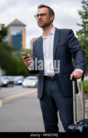 Reifen Geschäftsmann auf City Street bestellen Taxi mit Handy App Stockfoto